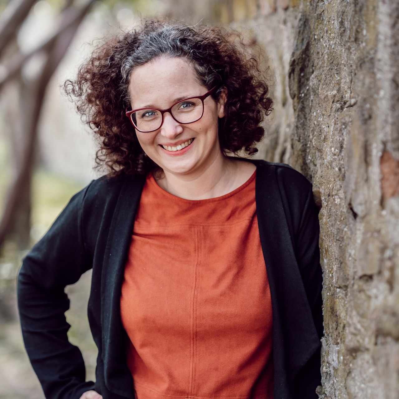 Agnes Rehor in der Natur an eine Mauer gelehnt.